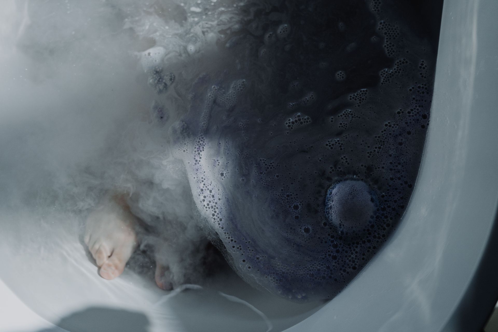 A calming bath scene with feet submerged in warm, foamy water, perfect for relaxation.